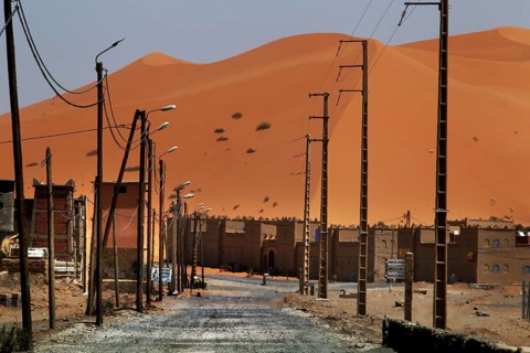Dunes on the horizon behind the modern settlement of Merzouga, Merzouga, Niger, Morocco