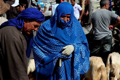 Man and woman in blue robes at a cattle market with goats, Guelmim, Morocco