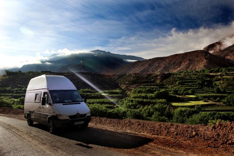 A van on a road with breathtaking views of the green fields of the mountains, Ait Bou Goumez, High