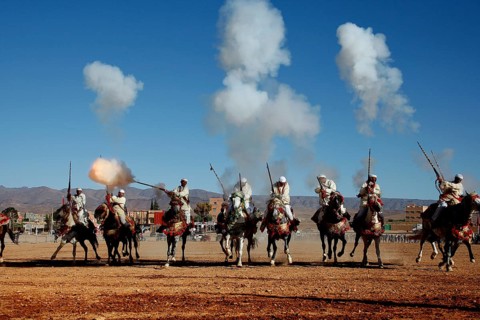 Group of riders fire guns and creates clouds of smoke during a traditional Fantasia ritual, El