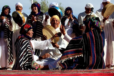 Gathering of men and woman wearing colorful Berber clothes holding drums, El Kelâa m'Gouna
