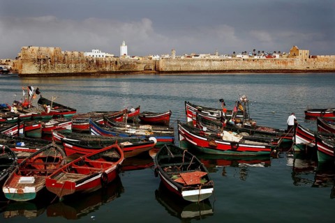 View of a medieval fortress from the harbor with lots of red and black boats, El Jadida, harbor,