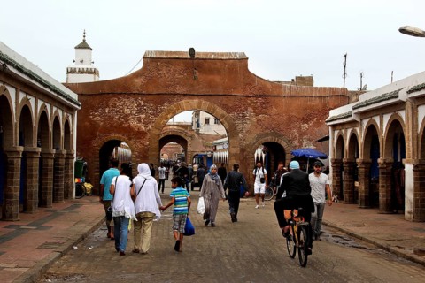 People walk through a historic stone gate in the souk of Essaouira, Essaouira, Morocco