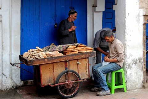 Vendor offers bread from a handcart in Essaouira souk, Essaouira, Morocco