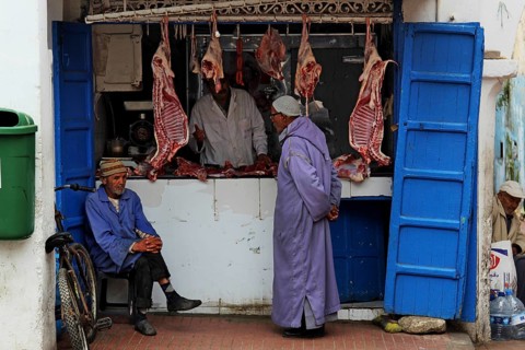 Men stand in front of a butcher shop in the souk of the old town of Essaouira, Essaouira, Morocco