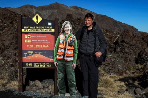 Rangers and hikers next to a warning sign at Tongariro Alpine Crossing, Tongariro National Park,