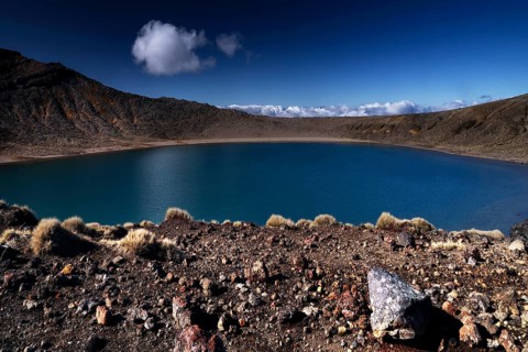 Tranquil Blue Lake in rough crater terrain against clear skies, Tongariro National Park, New