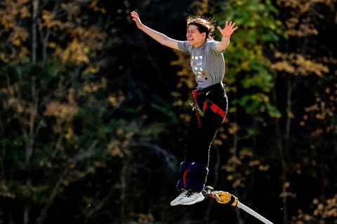 Female bungee jumping off Kawarau Bridge in the midst of autumn forest scenery, Queenstown, Otago,