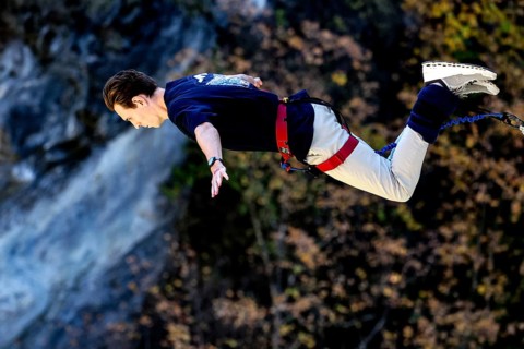 Jumper in horizontal prone position freefall over breathtaking landscape, Queenstown, Kawarau
