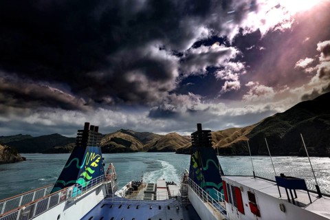 View of clouds and mountains on water from the stern of a ferry, Queen Charlotte Sound,