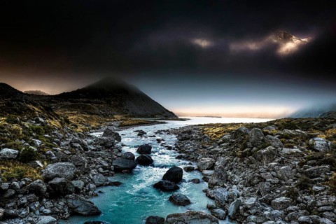 Dark mountain landscape with a narrow river surrounded by boulders in the evening light, Hooker