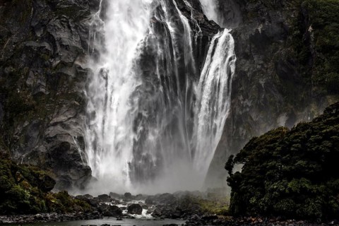 Powerful waterfall falls over rocks, creating an impressive spray, Milford Sound, New Zealand