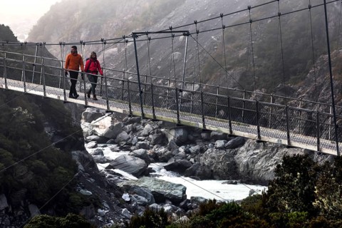 Hikers crossing a suspension bridge in a misty mountain landscape, Mt Cook, Hocker Valley Track,