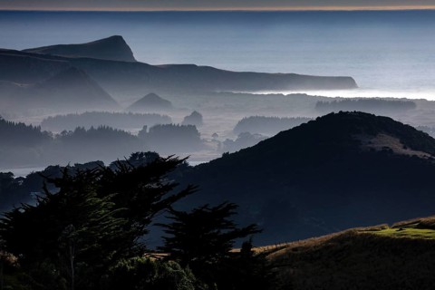 Blurred hills in morning fog along Highcliff Road, Otago Peninsula, New Zealand