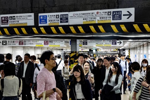 People flow through the busy train station surrounded by lots of signs, Tokyo, Japan