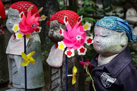 Row of jizo statues with colorful wind turbines at Zojo-ji Shrine in Minato, Tokyo, Tokyo, Japan