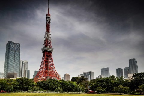 Tokyo Tower stands out on the horizon surrounded by green spaces and clouds, Tokyo, Japan