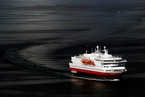 A Hurtigruten ship sails across the dark sea, Hammerfest, Finnmark, Norway