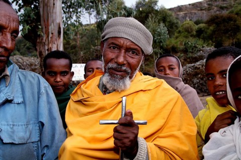 A pilgrim with a cross surrounded by other believers at Debre Libanos, Debre Libanos, Ethiopia