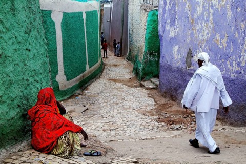 Two people wearing traditional clothes in a colorful alley in Harar, Harar, Ethiopia