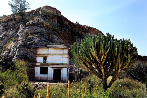 Entrance to Debre Mariam Krokor rock church in front of a steep rock face in natural surroundings,