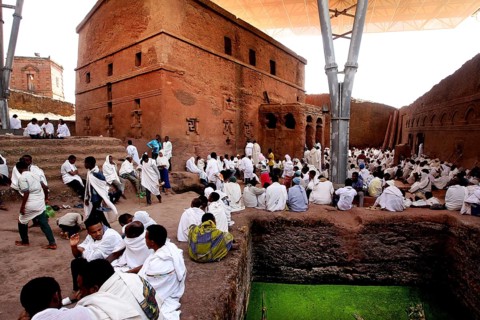 People wearing white clothes gather in front of the Bete Maryam rock church, Lalibela, Amhara,