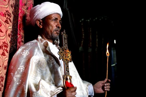 Priest with an ornate cross celebrates a ceremony in the Bete Meskel church. Expression of