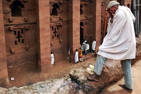 Pilgrim enters the imposing rock church of Bete Medhane Alem in Lalibela. The scene appears calm