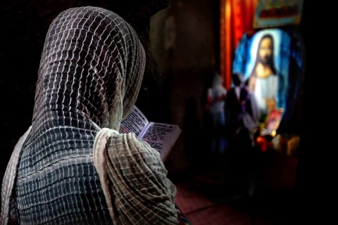 Person in church deepening in prayer in front of religious icons, Lalibela, Amhara, Ethiopia
