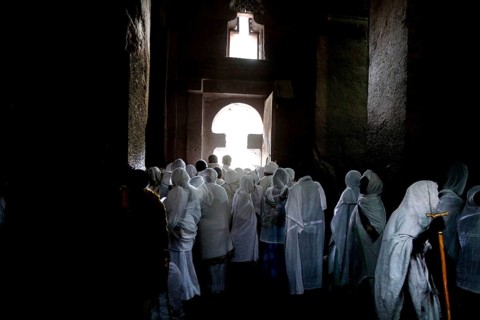 Believers wearing white clothes pray inside Bete Medhane Alem, Lalibela, Amhara, Ethiopia