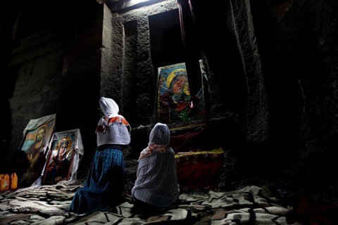 People praying in front of icons in Bete Medhane Alem, Lalibela, Amhara, Ethiopia