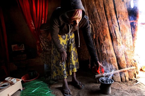 Lady carefully performs the coffee ceremony in her cozy abode. Smoke rises, Lalibela, Amhara,