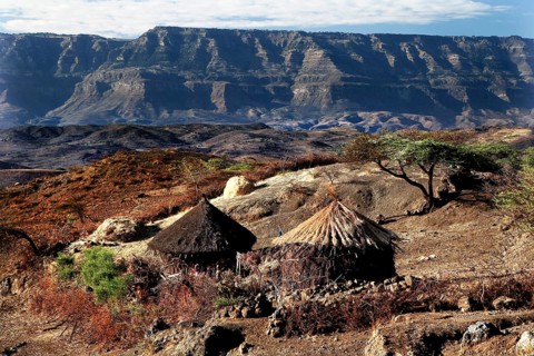 Traditional round huts against the majestic backdrop of the Lasta Mountains, Lalibela, Amhara,