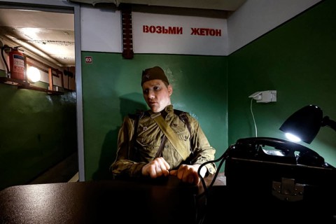 A person in military uniform sits in an atmospherically lit bunker in Plokstine, Plokštine, Telšiai