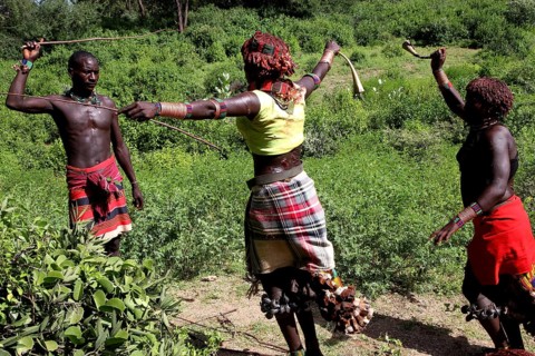 In the midst of lush nature, Hamer woman perform a whipping as part of a traditional initiation