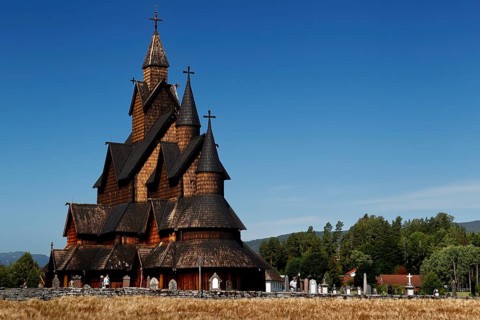 Historic stave church in Heddal with ornate wooden structure and blue sky in the background,