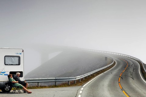Camper sitting on the side of the road on the foggy Atlantic road with steeply rising asphalt,