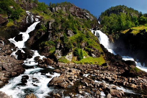 Låtefossen Waterfall flows powerfully over rocky landscape, surrounded by green nature, zero