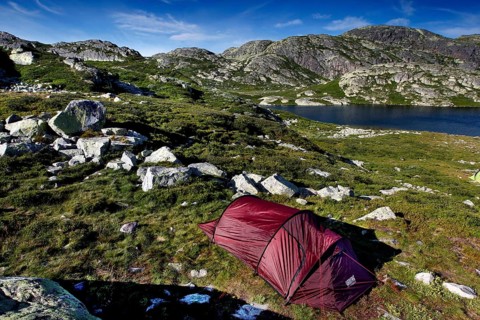 Red tent in mountainous seascape surrounded by untouched nature, Hardangervidda, Gausdal, Norway