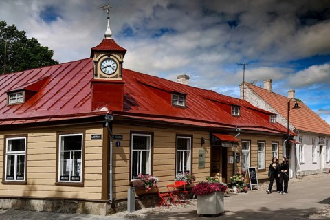 Historic building with red roof in the old town, people walking along the street, Kuressaare,