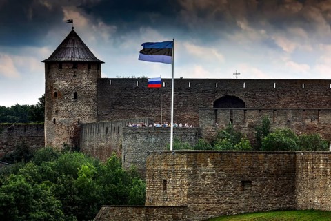 Close-up of Hermann Fortress with Estonian and Russian flags including dramatic clouds, Narva,