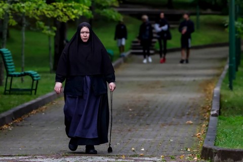 Nun with walking stick walks through the park in Kuremäe, Kuremäe, Pühtitsa, Estonia