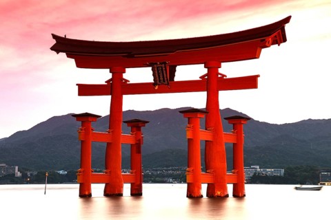 Illuminated torii of Itsukushima Shrine in water at night, Miyajima, Japan
