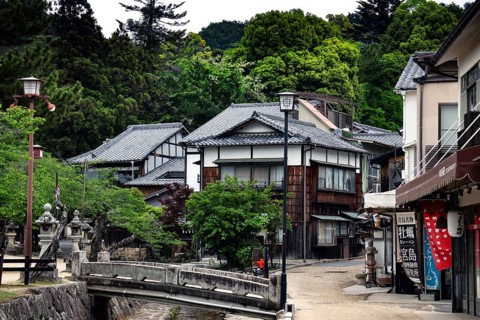 Traditional Japanese buildings on a quiet street surrounded by green vegetation, Miyajima, Japan
