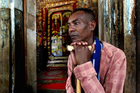 Believer is leaning on a stick at Ura Kidhane Mihret Church on Lake Tana, Lake Tana, Ethiopia