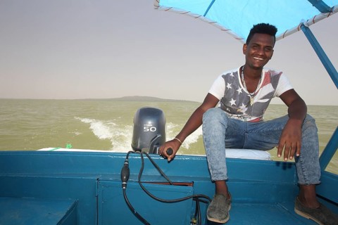 Captain rides a motor boat on Lake Tana under a blue sky, Lake Tana, Ethiopia