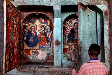 Person in front of icons in a decorated wooden structure, Tana Lake, Ura Kidhane Mihret, Ethiopia