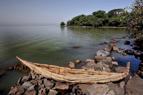 Papyrus boat is lying on a rocky shore with a view of Lake Tana, zero