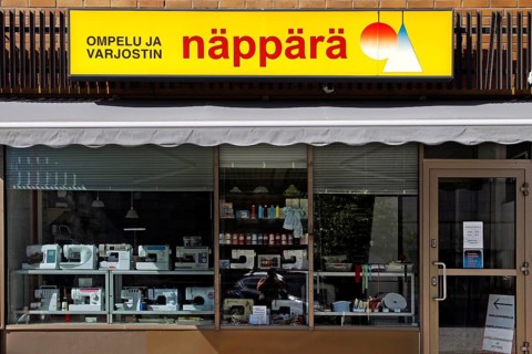Shop front with yellow Näppärä sign and shop window of a textile shop, Rovaniemi, Finland
