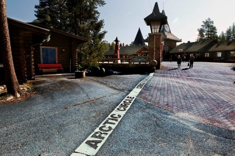 Arctic circle marking on cobblestones in front of picturesque buildings, Napapiiri, Finland